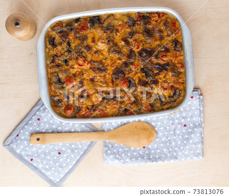 Casserole in a baking tray on a wooden table. The finished dish is baked in the oven. 73813076