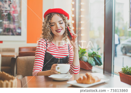 Happy young woman chatting and eating in european cafe 73813860
