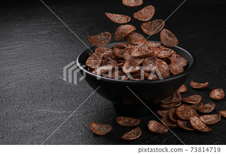 Falling chocolate corn flakes on black background Falling chocolate corn flakes on black background 73814719