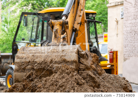 Excavator bucket pours ground. Repair work plumbing. 73814909