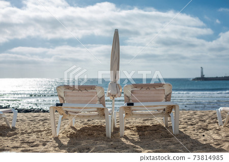 Two empty chaise-lounges on the beach in the city of Costa Teguise. Two empty chaise-lounges on the beach in the city of Costa Teguise. 73814985