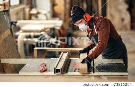 Woodworker cutting wood in workshop Woodworker cutting wood in workshop 73815294