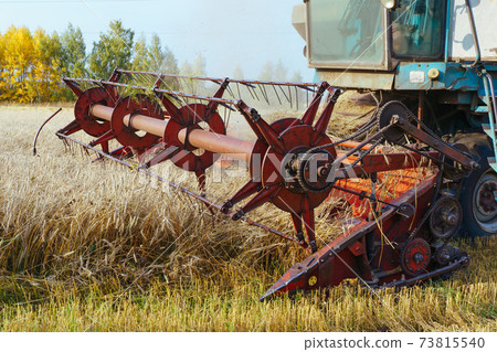 Combine harvester harvests ripe wheat. Concept of a rich harvest. Agriculture image. Combine harvester harvests ripe wheat. Concept of a rich harvest. Agriculture image. 73815540