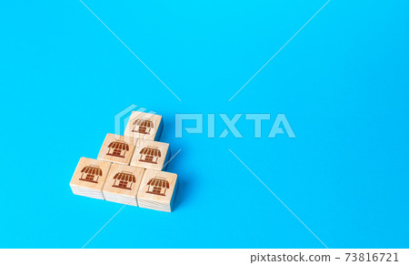 Block pyramid with shop symbols. Franchising concept. Business franchise. Commercial association. Business management. Retail and trade. Organization and structuring. Investment in commerce. Block pyramid with shop symbols. Franchising concept. Business franchise. Commercial association. Business management. Retail and trade. Organization and structuring. Investment in commerce. 73816721