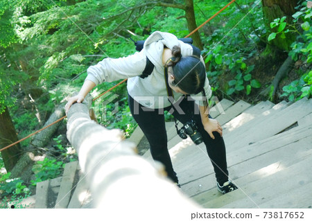 A woman who is tired and stops on the stairs in the mountains A woman who is tired and stops on the stairs in the mountains 73817652