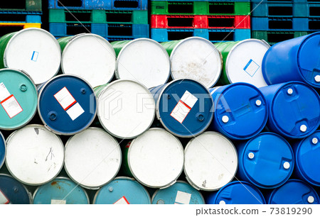 Old chemical barrels in front of stacked plastic pallet at the factory. Blue and green oil drum. Steel and plastic oil tank. Toxic waste warehouse. Hazard chemical barrel. Industrial waste in drums. 73819290