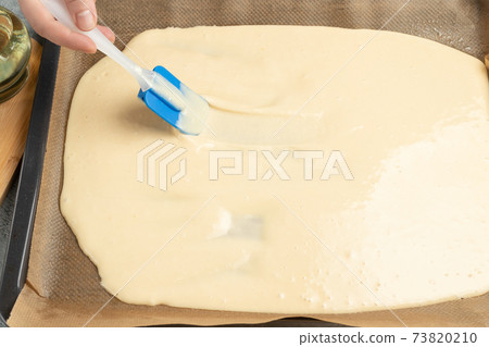 Spreading the dough for the sweet roll on a baking sheet Spreading the dough for the sweet roll on a baking sheet 73820210