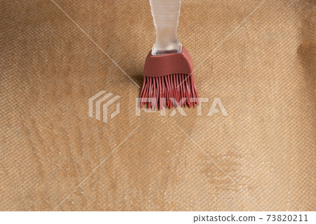 Greasing a baking sheet covered with baking paper Greasing a baking sheet covered with baking paper 73820211