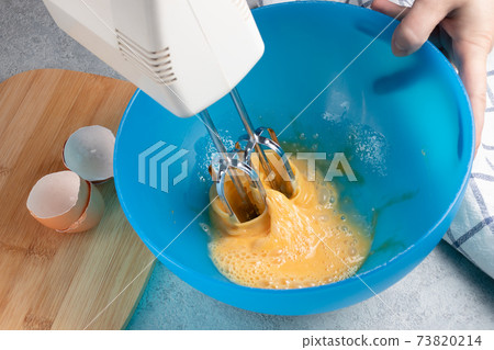Whisking fresh chicken eggs in a blue bowl Whisking fresh chicken eggs in a blue bowl 73820214