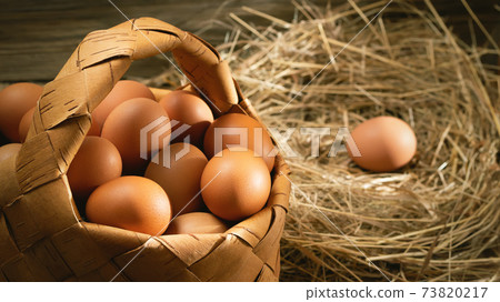 Fresh brown chicken eggs in a basket and in a nest from hay in a barn, horizontal banner Fresh brown chicken eggs in a basket and in a nest from hay in a barn, horizontal banner 73820217