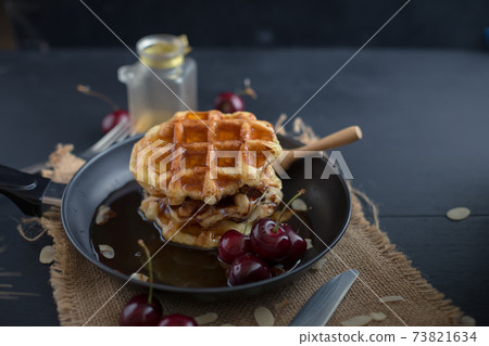 Honey on waffles with cherry berries on dark wooden background. breakfast concept Honey on waffles with cherry berries on dark wooden background. breakfast concept 73821634