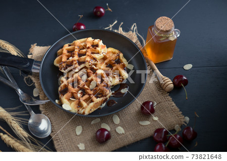 Honey on waffles with cherry berries on dark wooden background. breakfast concept Honey on waffles with cherry berries on dark wooden background. breakfast concept 73821648