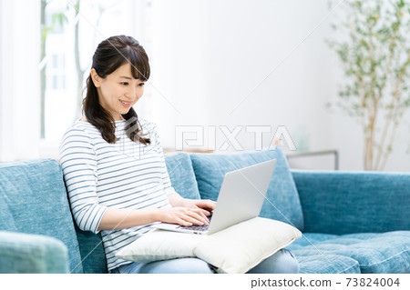女人在客廳裡玩一台筆記本電腦 女人在客廳裡玩一台筆記本電腦 73824004