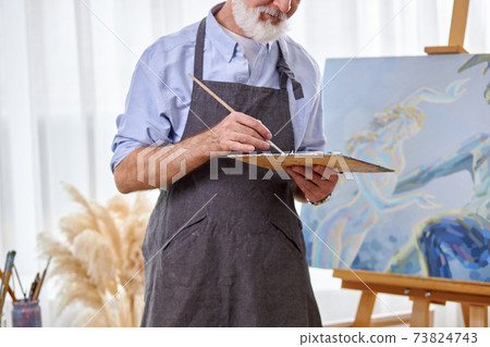 cropped artist taking paint with brush from a palette 73824743