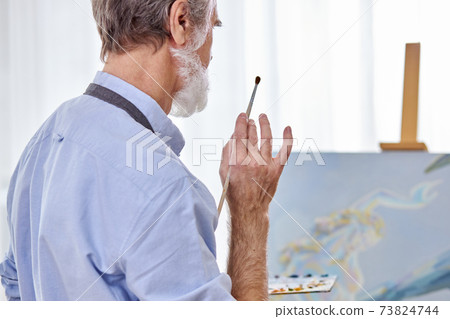 rear view on elderly artist man holding paintbrush in hands 73824744