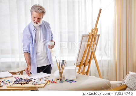 senior artist draws a sketch on paper, and then on canvas senior artist draws a sketch on paper, and then on canvas 73824746