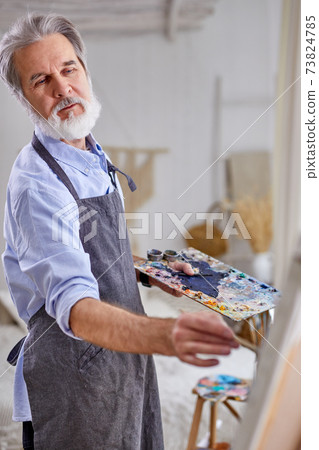 indoor shot of senior caucasian man painting picture on canvas indoor shot of senior caucasian man painting picture on canvas 73824785