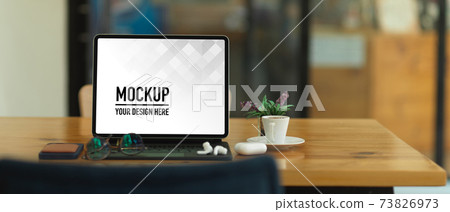 Wooden table with tablet, keyboard, eyeglasses, accessories and cup in home office 73826973