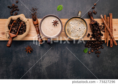 Roasted coffee beans with coffee powder and flavourful ingredients for make tasty coffee setup on dark stone background. 73827296