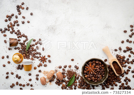 Background of various coffee , dark roasted coffee beans , ground and capsules with scoops setup on white concrete background with copy space. Background of various coffee , dark roasted coffee beans , ground and capsules with scoops setup on white concrete background with copy space. 73827334