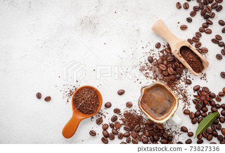 Background of various coffee , dark roasted coffee beans , ground and capsules with scoops setup on white concrete background with copy space. Background of various coffee , dark roasted coffee beans , ground and capsules with scoops setup on white concrete background with copy space. 73827336