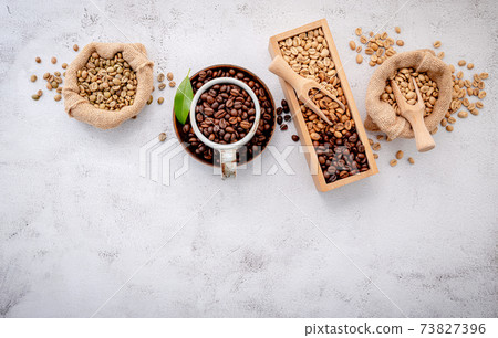 Roasted coffee beans with scoops setup on white concrete background. Roasted coffee beans with scoops setup on white concrete background. 73827396