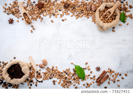 Roasted coffee beans with scoops setup on white concrete background. 73827451