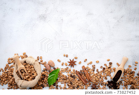 Roasted coffee beans with scoops setup on white concrete background. 73827452