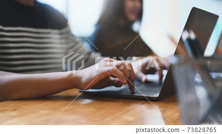 Close up view of young man hands typing on keyboard of laptop at modern co working office. Close up view of young man hands typing on keyboard of laptop at modern co working office. 73828765
