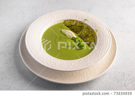 Homemade soup puree of green peas, coconut milk with tuil and cheese quenelle 73830939