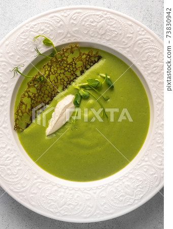 Vertical view soup puree of green peas and coconut milk with tuil and cheese quenelle Vertical view soup puree of green peas and coconut milk with tuil and cheese quenelle 73830942