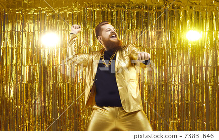 Happy young guy in funny shiny golden suit dancing and having fun at disco party Happy young guy in funny shiny golden suit dancing and having fun at disco party 73831646