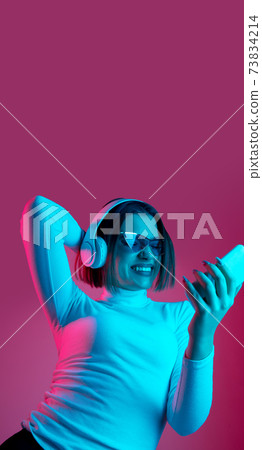 Caucasian woman's portrait isolated on pink studio background in multicolored neon light Caucasian woman's portrait isolated on pink studio background in multicolored neon light 73834214