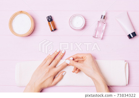 Home nail care, female hands apply nourishing cuticle cream Home nail care, female hands apply nourishing cuticle cream 73834322