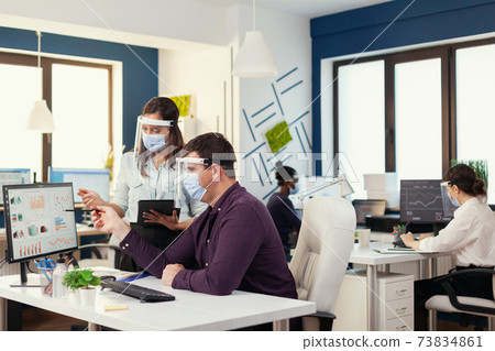 international team doing financial analysis wearing face mask as safety precaution 73834861