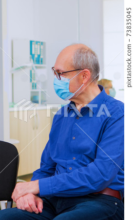 Patients with masks talking sitting on chairs keeping social distance 73835045