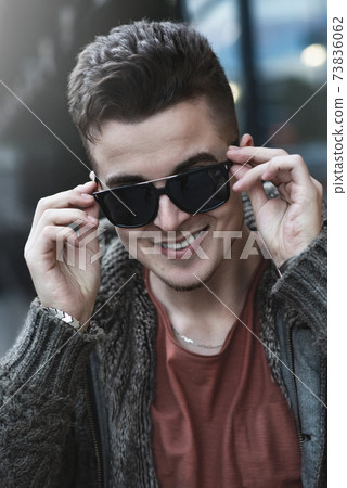 Closeup portrait of a casual young man with sunglasses looking at the camera at street Closeup portrait of a casual young man with sunglasses looking at the camera at street 73836062