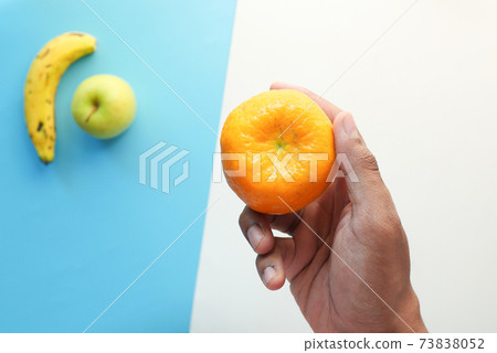 hand holding ripe orange fruit on color background  73838052
