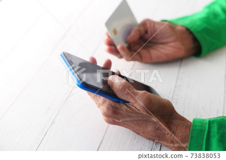 elderly women hand holding credit card and using smart phone shopping online  73838053