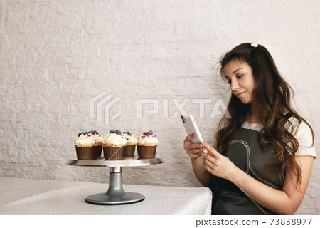 A girl blogger takes photos of cakes and cupcakes for her followers 73838977