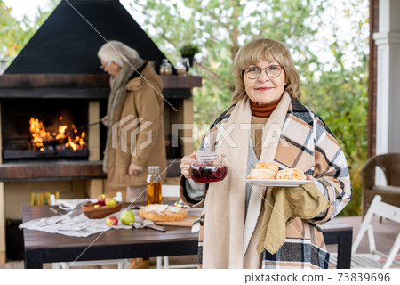 Happy grandmother in eyeglasses and checkered woolen plaid holding food 73839696