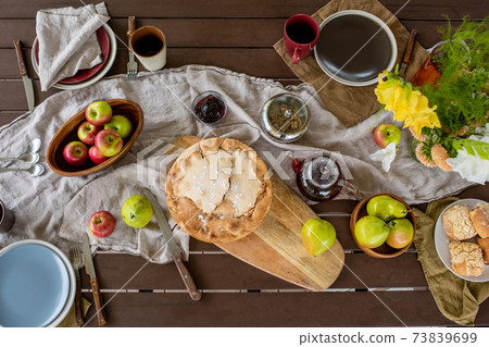 Overview of rectangular wooden table served with homemade pie and other food Overview of rectangular wooden table served with homemade pie and other food 73839699