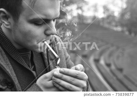 Guy smokes a cigarette outside, portrait, close-up 73839877