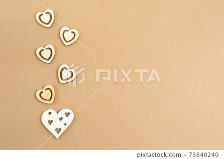 Wooden hearts on a pastel craft paper background. Abstract background with wood cut shapes. Sainte Valentine, mother's day, birthday greeting cards, invitations. Copy space. 73840240