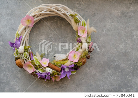 Handmade Easter wreath with flowers and a bird on a gray background Handmade Easter wreath with flowers and a bird on a gray background 73840341