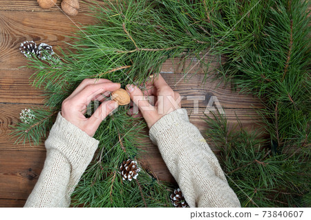 DIY christmas wreath in eco style. Woman makes a wreath on a wooden 73840607