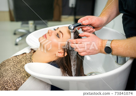 Hairdresser begins to wash hair 73841074