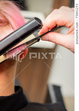 Hairdresser straightening the short hair 73841253