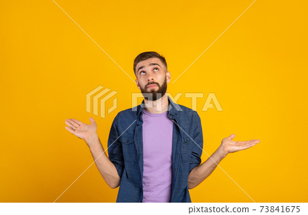 Who knows. Confused Caucasian guy shrugging shoulders on orange studio background, panorama Who knows. Confused Caucasian guy shrugging shoulders on orange studio background, panorama 73841675