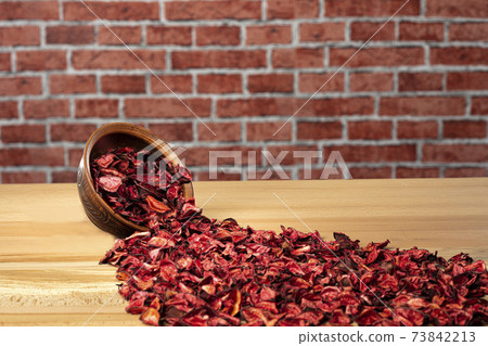 Red dried rose are scattered on the wooden background and plate Red dried rose are scattered on the wooden background and plate 73842213